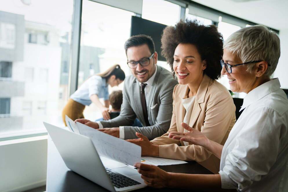 A group of three racially diverse employees looking over papers at a desk