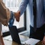 Workers in an office share a handshake.