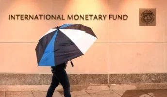 Man holding an umbrella outside of the IMF
